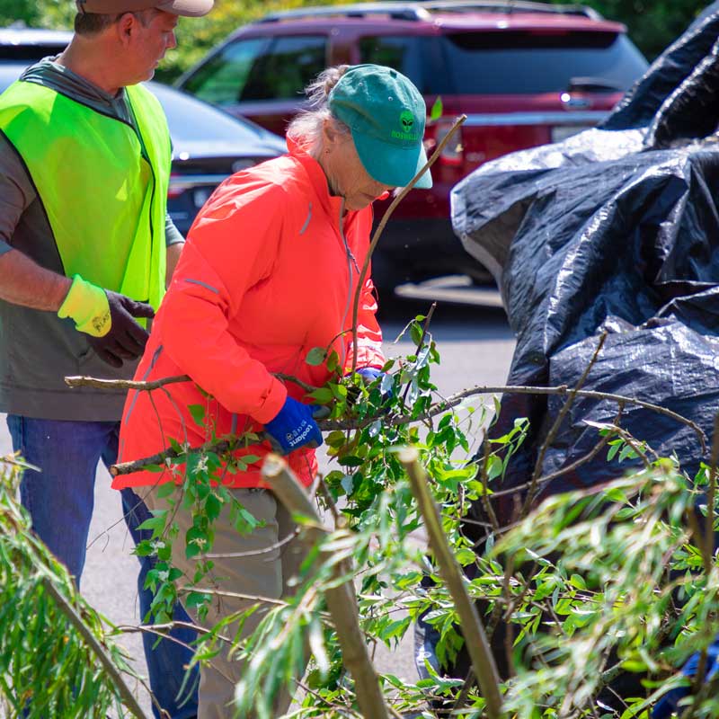 Woman in orange jacket and blue hat participating in the Skiles Test Nature Park Cleanup Day